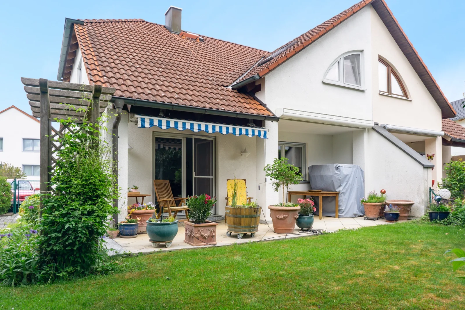 Gartenseite eines Wohnhauses mit Terrasse und Bepflanzung
