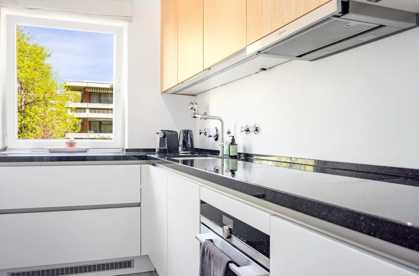 Helle Küche mit Fenster und schwarzen Arbeitsflächen